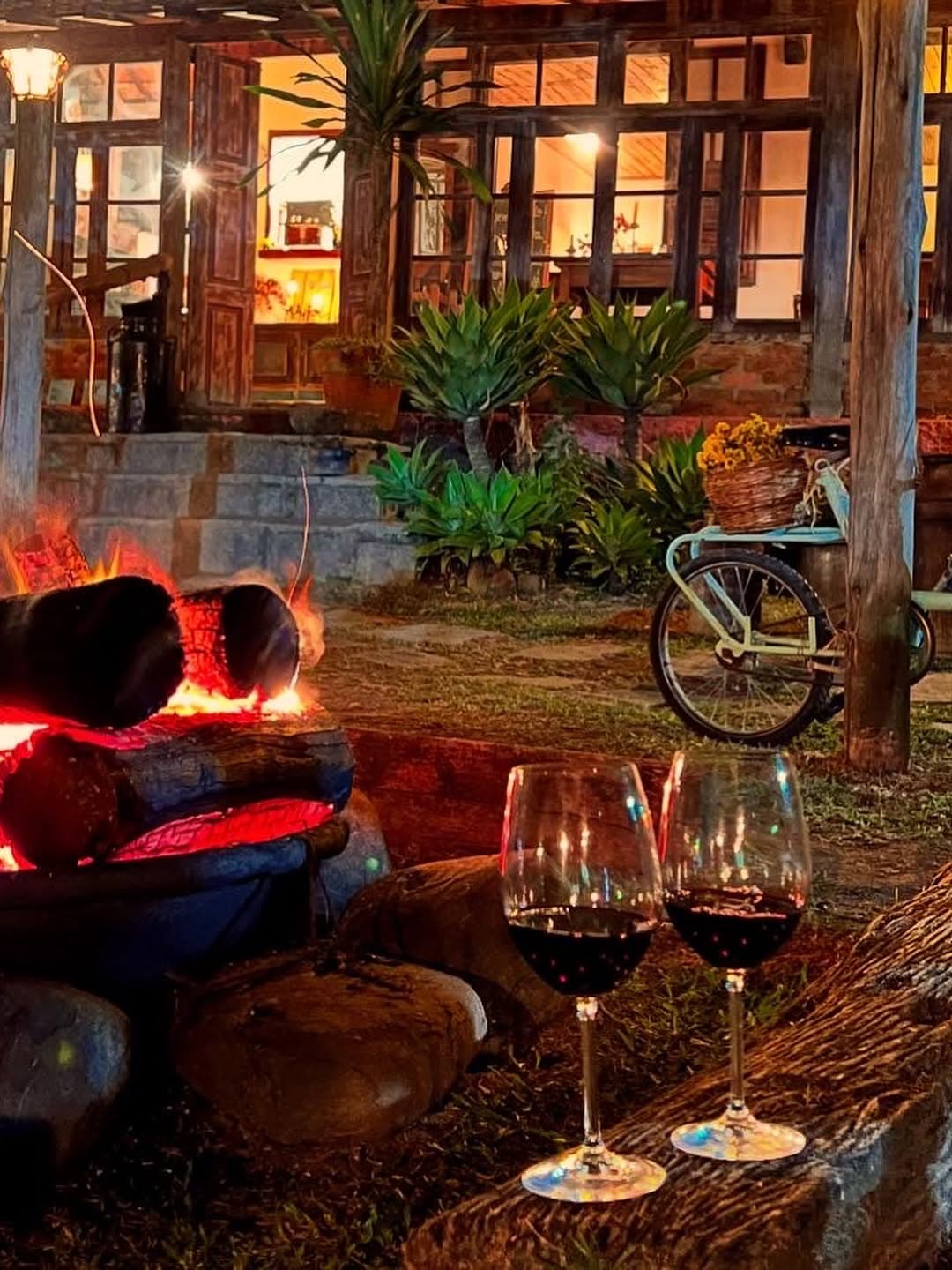 Taças de vinho próximas ao fogo e à casa iluminada